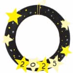 A handmade New Years wreath crafted from a black paper plate, adorned with yellow stars. The lower stars display 2025 in bold black numbers. Bright yellow dots accent the wreath, which gracefully hangs by a yellow and white striped string.