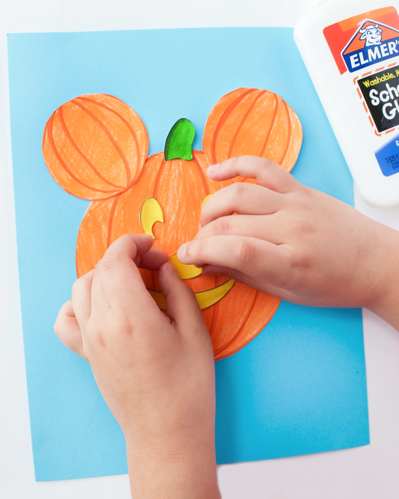 child gluing mickey pumpkin craft