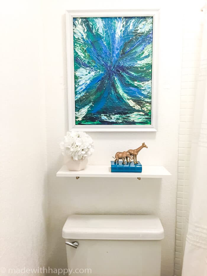 50 dollar bathroom makeover.  We turned this off-white and brown 80's bathroom into a modern dream with just a few changes.  We were able to paint the tile and paint the vanity top changing the look of the bathroom dramatically.  Bathroom Makeover on a budget.  DIY Bathroom.  Modern Blue Bathroom.  www.madewithhappy.com