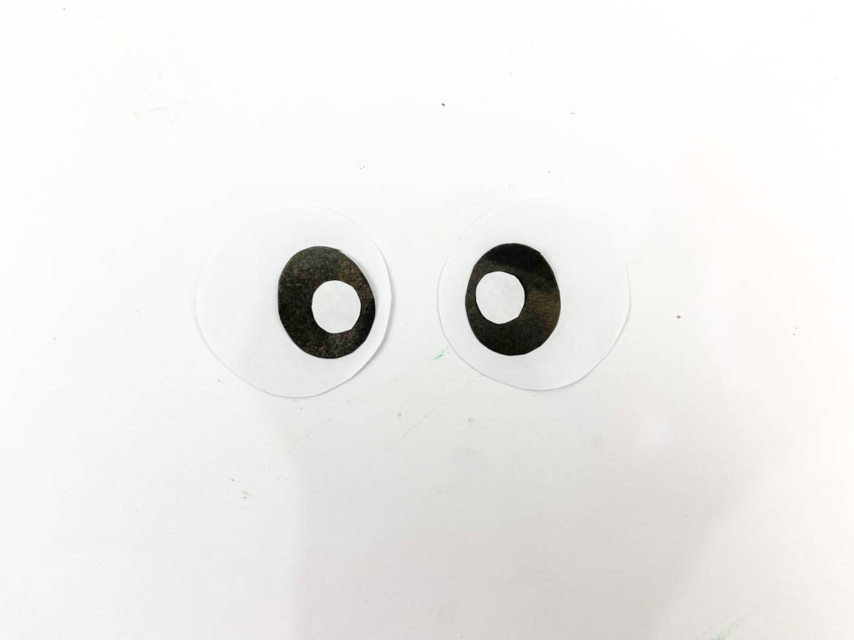 cut two white circles out of white paper draw on eyes