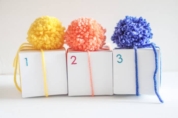 Three boxes with pom poms on them.