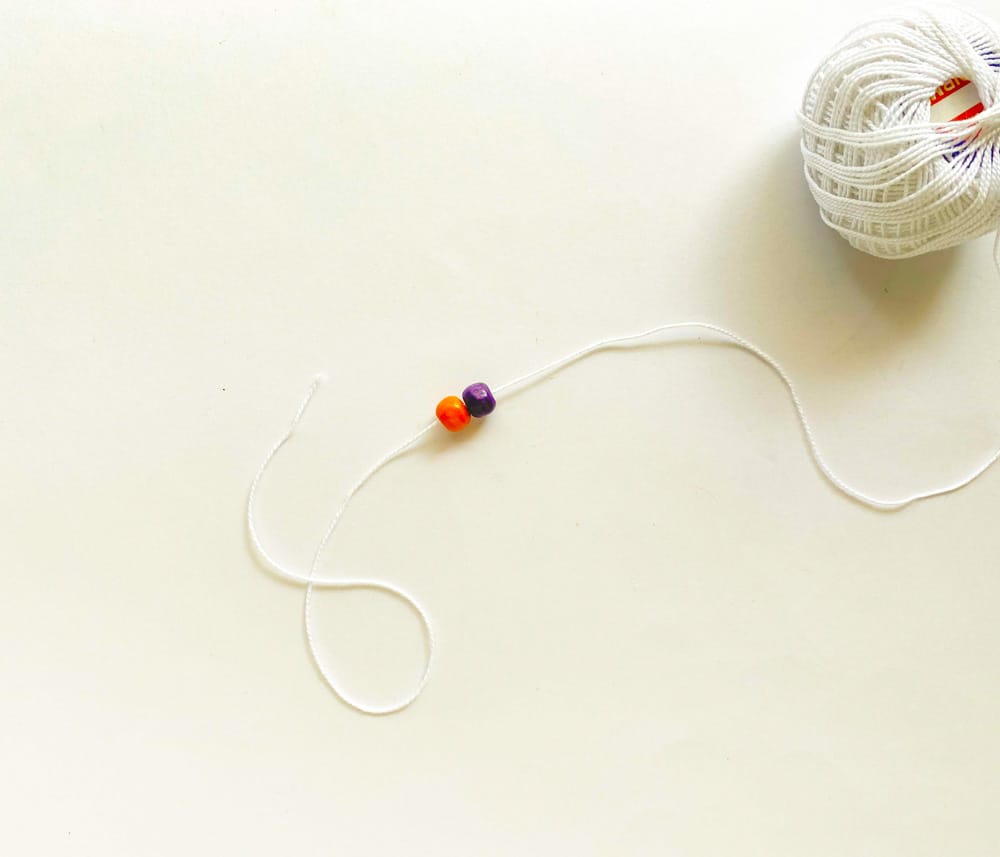 Take the beads and thread. Insert colourful beads through the thread, tie a knot at the end so the beads stay in place.