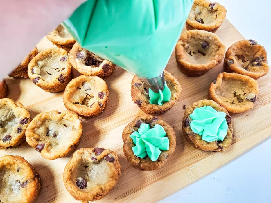 piping green frosting onto cookie cups