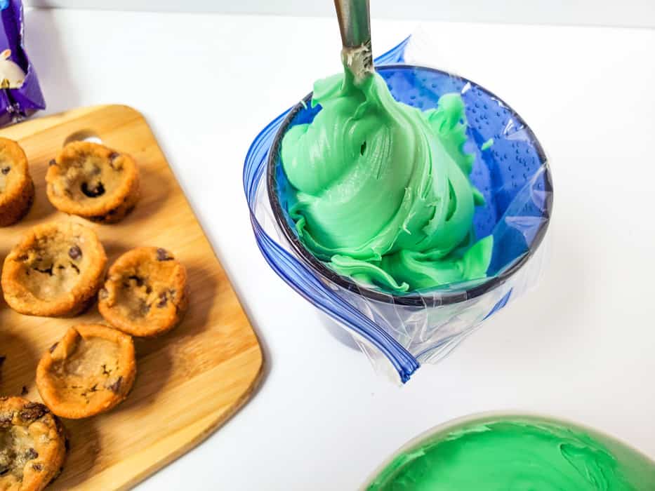 placing green frosting into piping bag