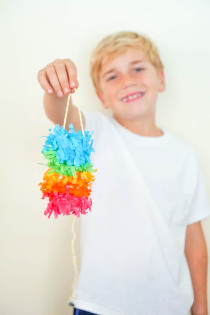 kid holding rainbow toilet paper pinata