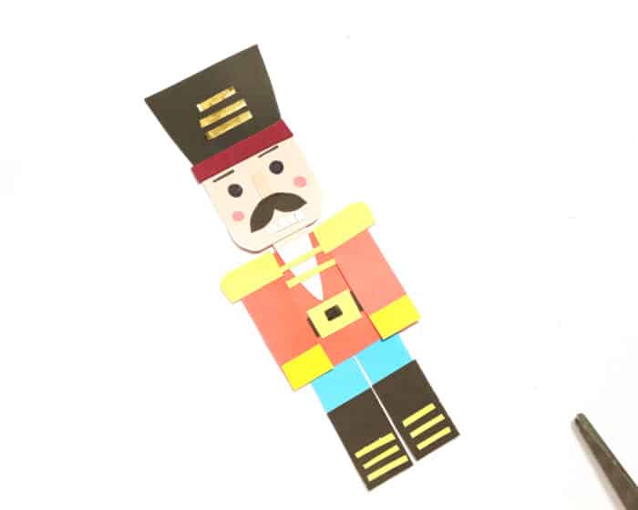 Then, glue the moustache and teeth, and finally, use marker pens to draw the nutcracker’s face, 