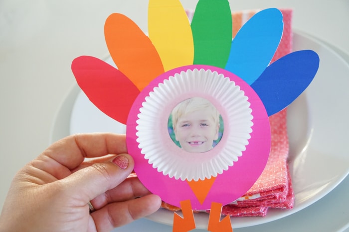 If you are using the sticker paper, then peel the back of the picture and place it inside the cupcake liner. If you are using a standard picture, then place the glue on the back of the picture and then place into the cupcake holder. Lastly, glue the cupcake liner to the turkey! Viola you have yourself the cutest paper turkey craft ever!