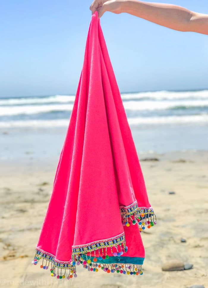 hand holding pink blanket at beach