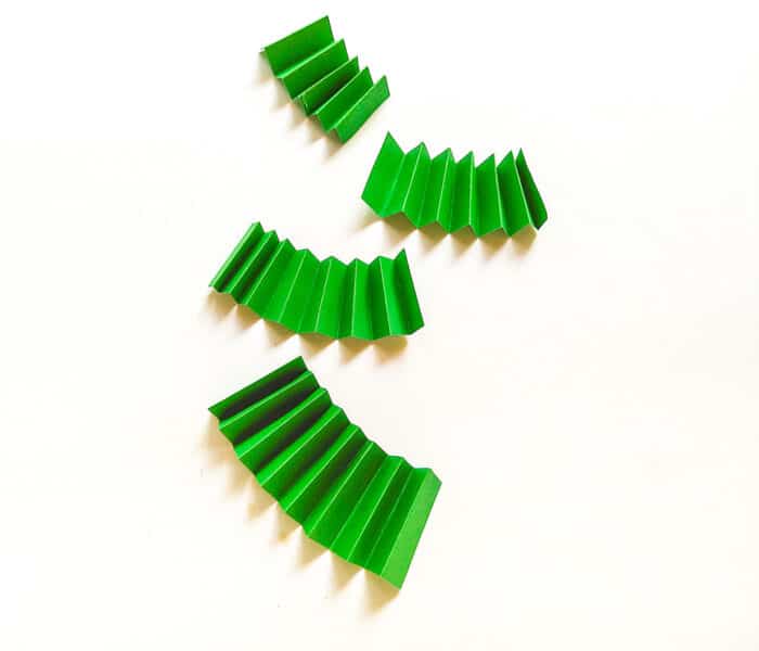 Fold the green craft paper strips into accordion folds.