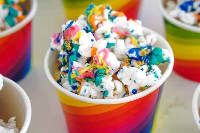 Rainbow drizzled popcorn. There is nothing sweeter than turning up the color on your popcorn snack with this super fun rainbow popcorn. Rainbow snacks for St. Patrick's Day. Rainbow food.