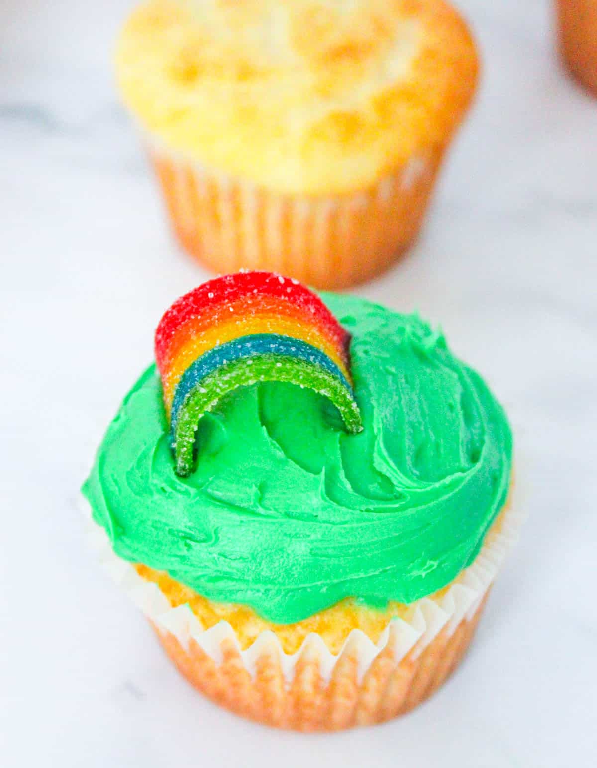 add rainbow candy to green frosted cupcake