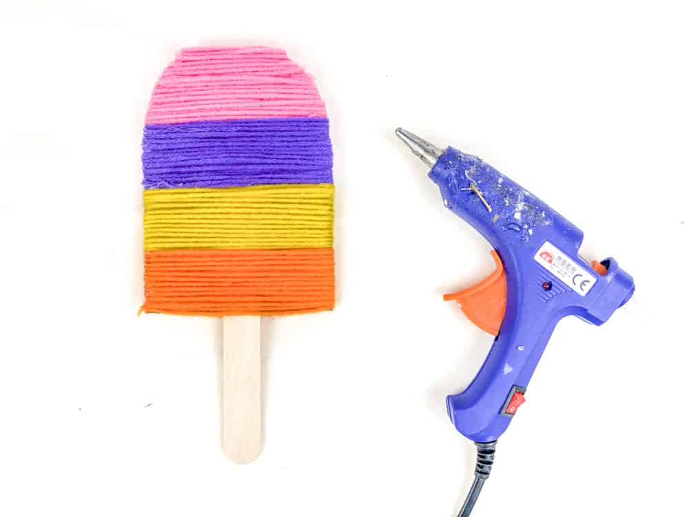carefully glue popsicle stick between yarn and cardboard