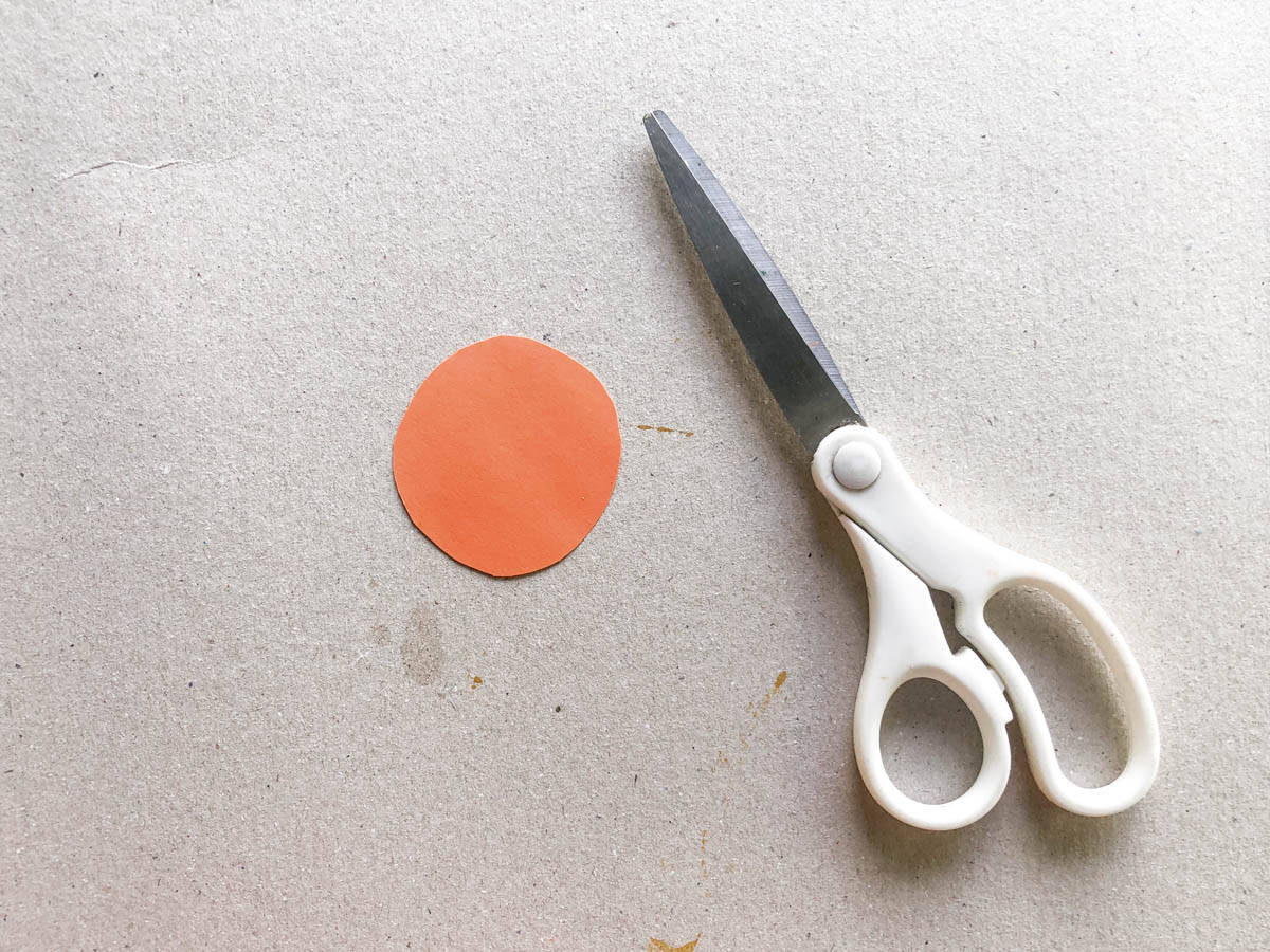 cut circle out of orange paper for pumpkin craft