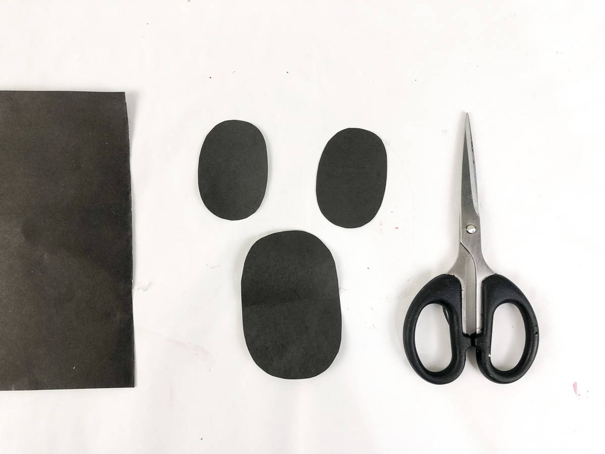 cut out three ovals out of black paper for paper plate ghost face