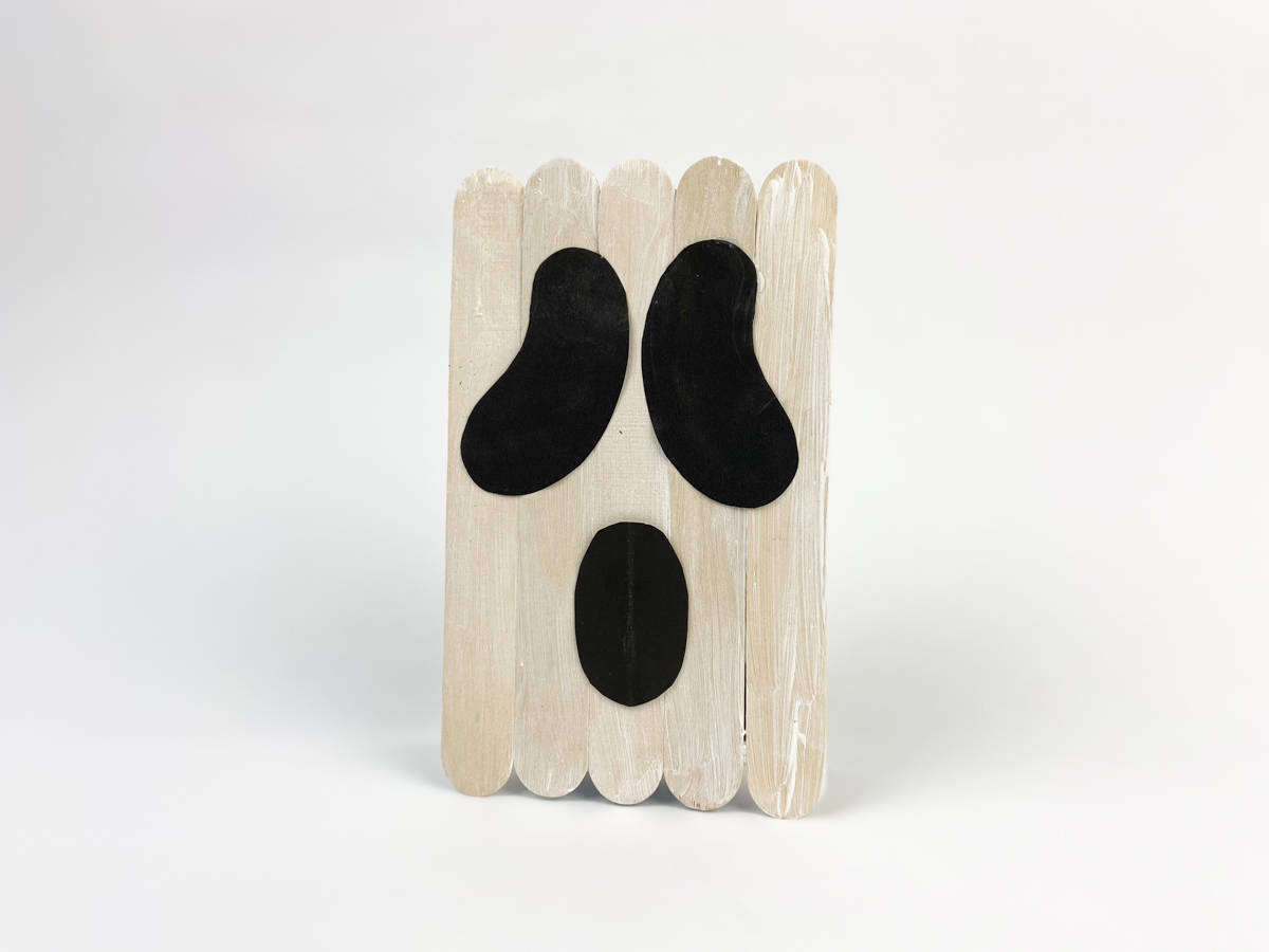 glue ghost face to front of popsicle stick ghost