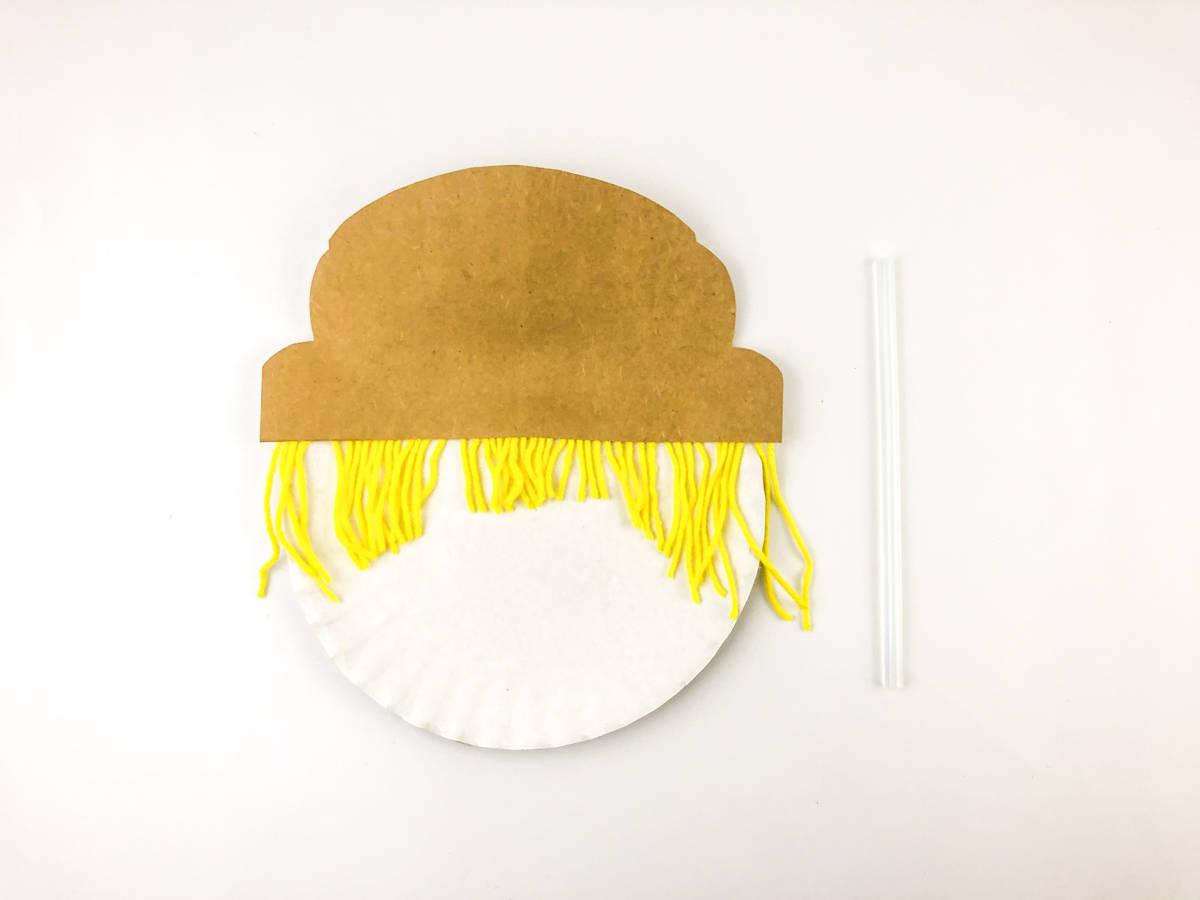 glue scarecrow hair and hat to paper plate
