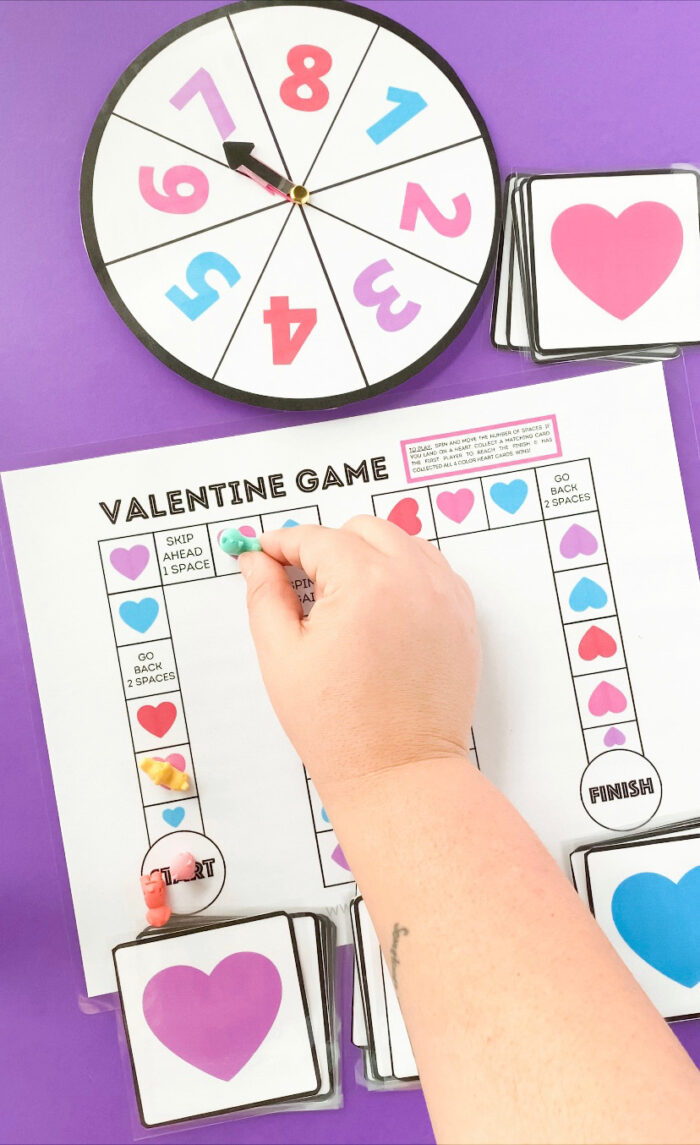 child's hand playing valentine board game