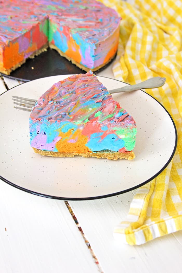 Slice next to full cheesecake of colorful cheesecake