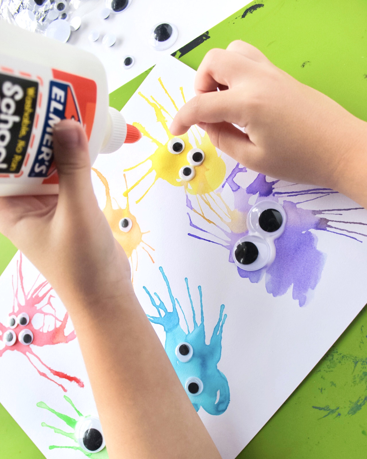 child gluing googly eyes on watercolor monsters craft