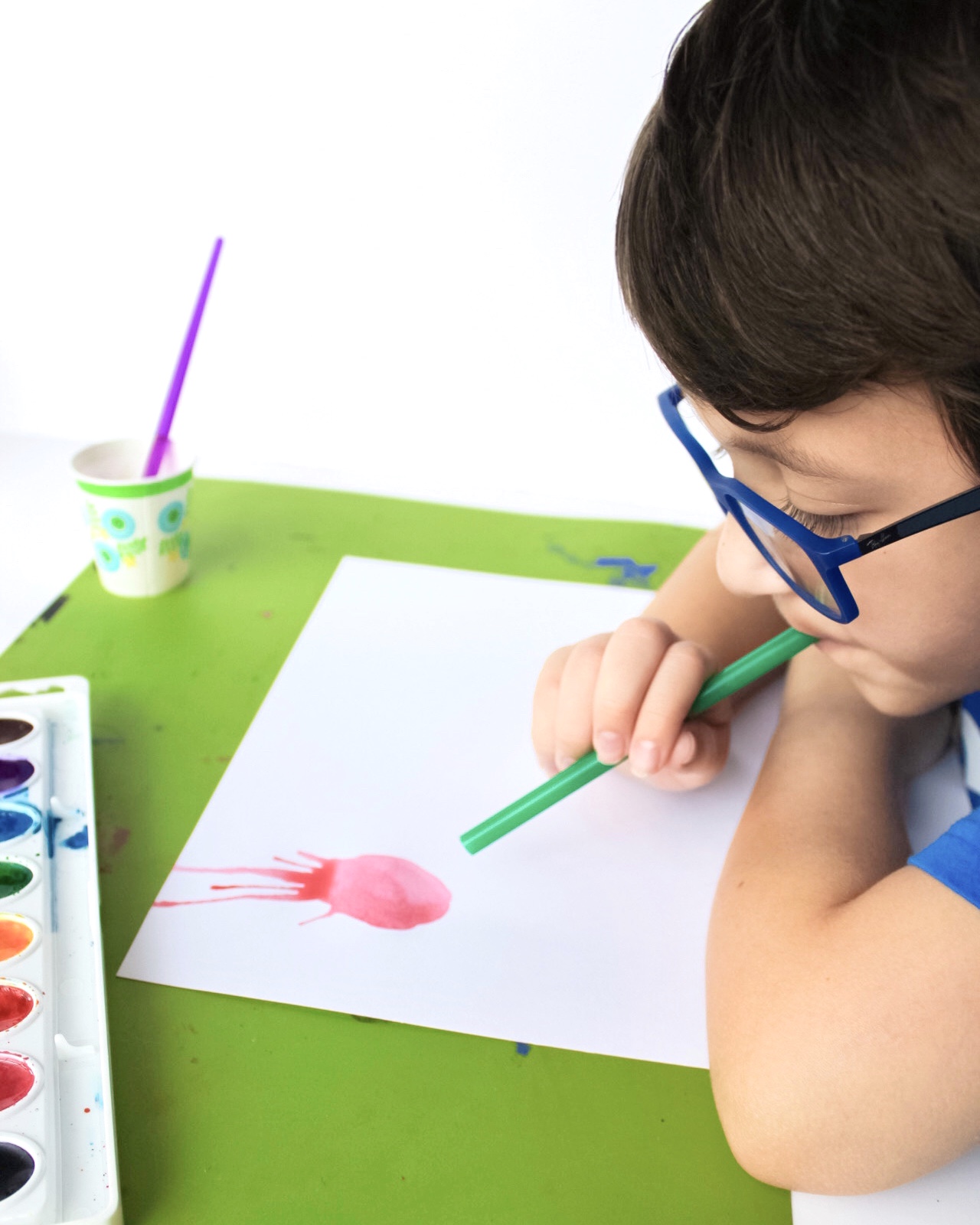 child blowing watercolor with straw